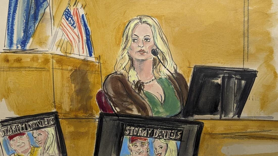 Auf dieser Gerichtszeichnung sagt Stormy Daniels im Zeugenstand aus, während ein Werbebild für eine ihrer Shows auf Monitoren angezeigt wird. Foto: Elizabeth Williams/AP/dpa