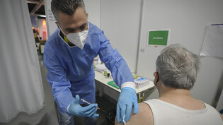 ARCHIV - Ein Mitarbeiter im Gesundheitswesen impft in Wien einen Mann gegen Corona. Foto: Vadim Ghirda/AP/dpa