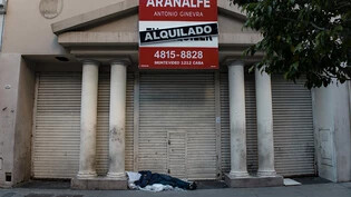 Eine Person schläft während des Generalstreiks vor einem Gebäude. Foto: Cristina Sille/dpa