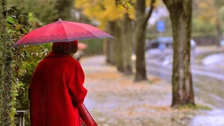 Eine Frau wartet im strömenden Regen auf die Ankunft des Stadtbusses.