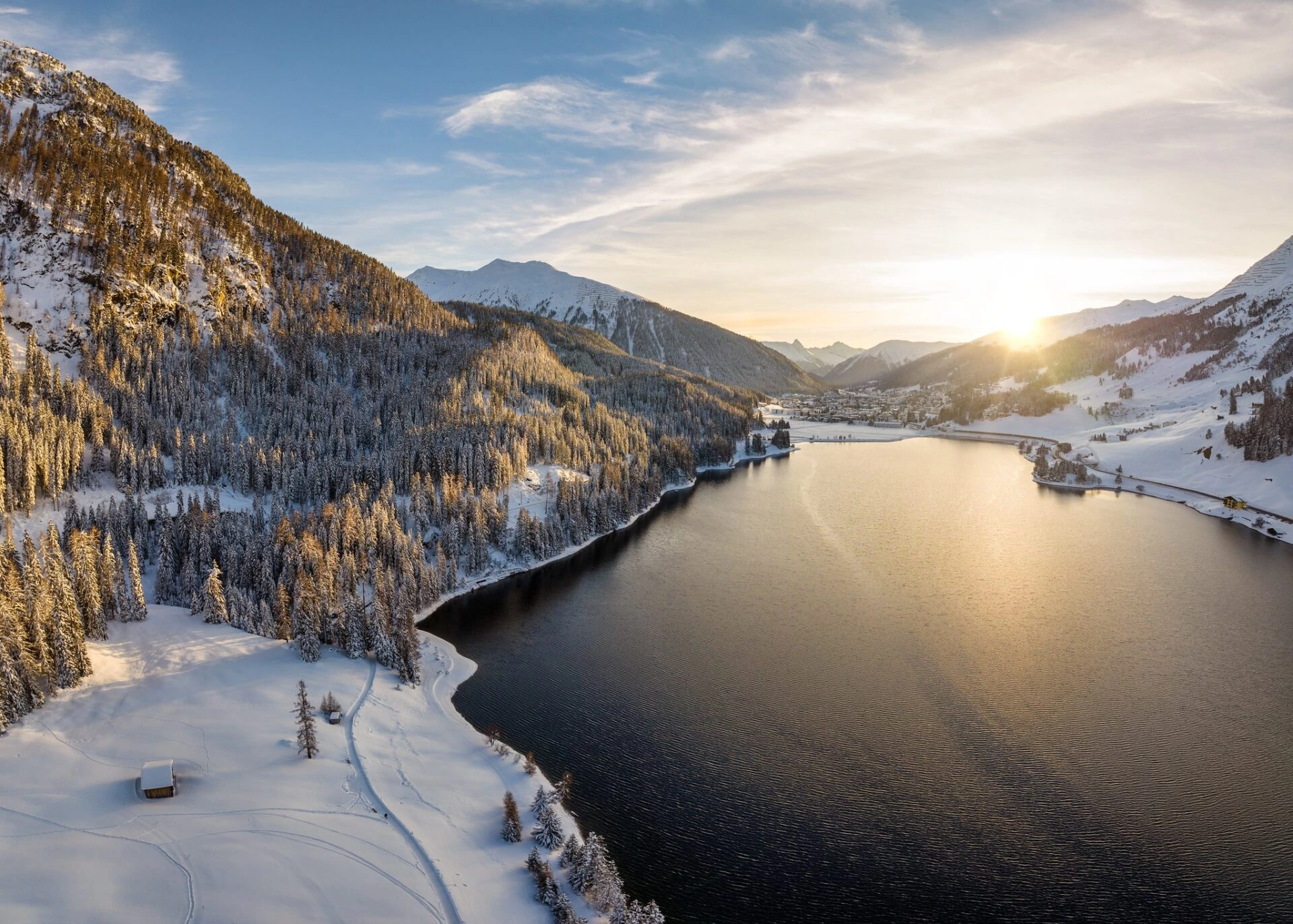 Vereister Davosersee in Graubünden mit verschneiten Bergen und Winterstimmung