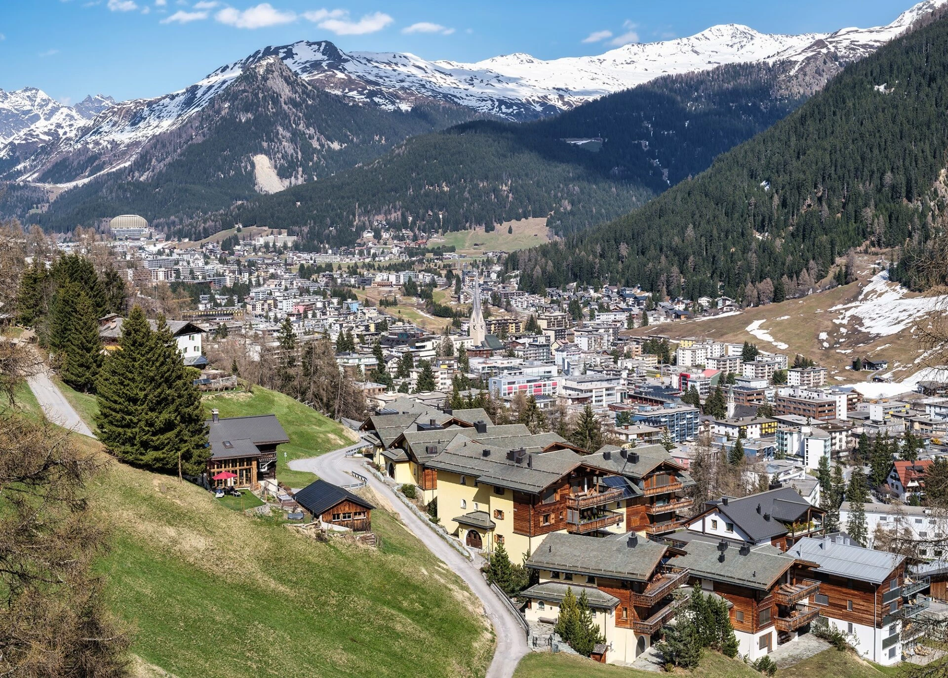 Blick über Davos im Landwassertal mit Häusern, Wiesen und umliegenden Alpen